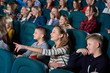 © serhiibobyk - Shot of cheerful kids enjoying a movie at the cinema smiling pointing at the screen excitedly people childhood kids youth teenagers emotions expressive excitement entertainment leisure.