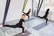 © Kateryna Muzhevska - Young women doing aerial yoga exercise