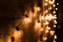 String of vintage light bulbs against a concrete wall with shallow depth of field