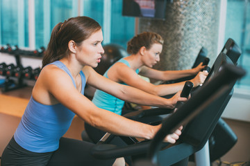 Two Women Working out Hard on Bikes in Gym