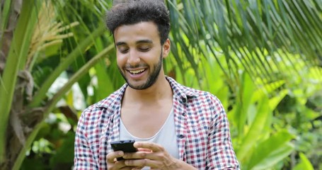 Poster - young man using cell smart phone smiling outdoors mix race guy closeup chatting online over green tr
