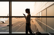 © kieferpix - Young woman traveler using her smartphone while walking through airport.
