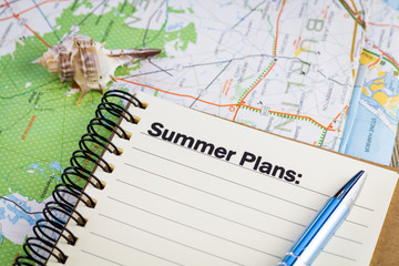 Summer plans list concept on notebook and map