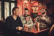 © Nejron Photo - Cheerful old friends having fun and drinking draft beer in pub.