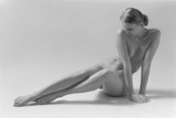 Beautiful blonde nude woman sitting on white background. Black & white film. Film grain. Copy space for text.