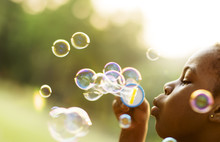 Children Is Playing Bubbles In A Park