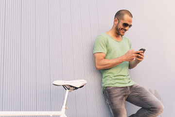 Handsome young man with mobile phone and fixed gear bicycle.