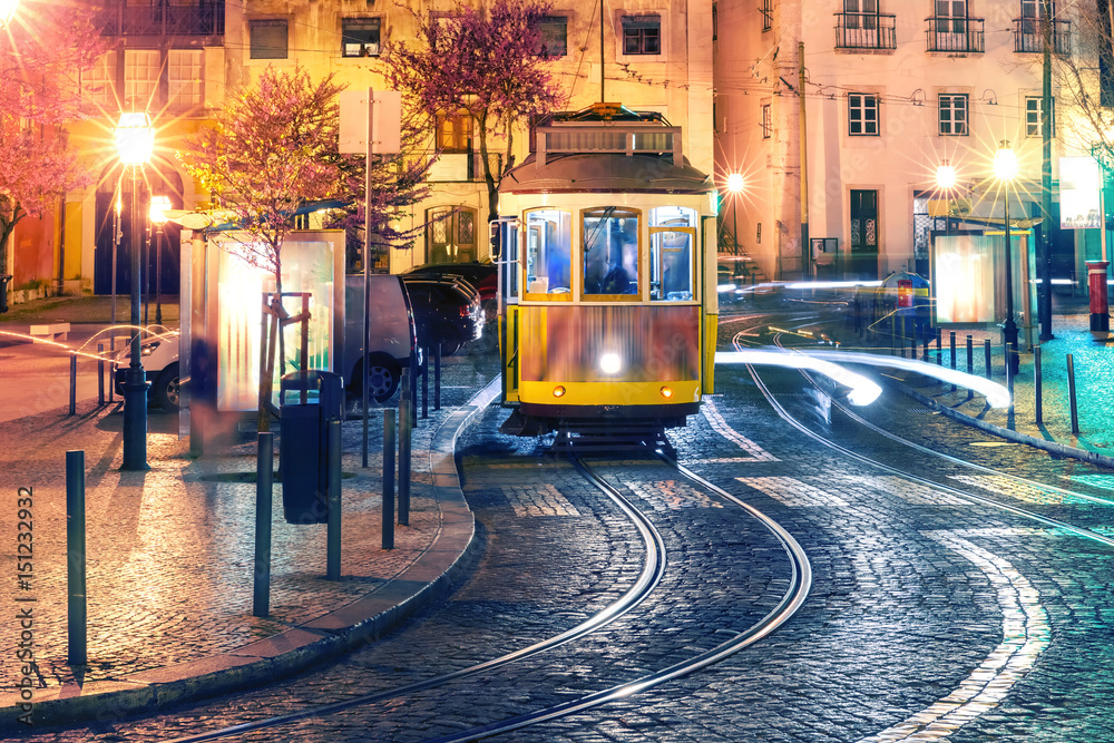 Famous vintage yellow 28 tram of of Alfama, in the oldest district of the Old Town, at night, Lisbon, Portugal - obrazy, fototapety, plakaty 