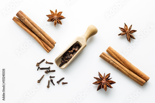 Fotografía cloves with wooden scoop and cinnamon on white