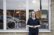 © Maskot - Portrait of confident female owner standing outside eyeglasses workshop