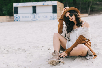 Beautiful model in hat and dress in hippie style posing on summer beach.