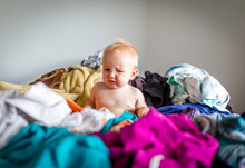 Cute Baby Disrupts Household Chores By Sitting In Pile Of Clothes On Bed