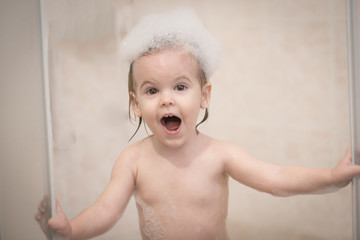 Adorable child blond girl with soap suds on hair taking bath