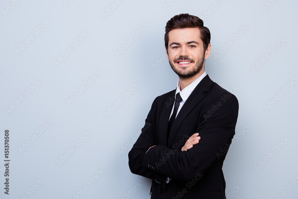 Photo Stock Happy smiling young handsome guy in formal wear with crossed  hands standing half-turned against gray background | Adobe Stock