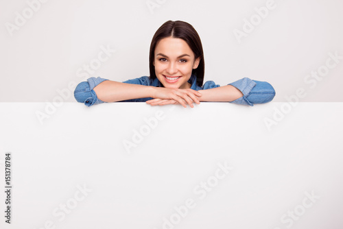 Cuadros en Lienzo Pretty smiling woman in jeans shirt leaning on the top of the white banner, pla