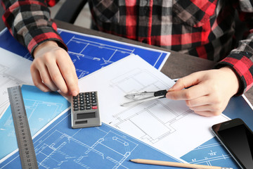 Wall Mural - Male engineer hands working with blueprints on table