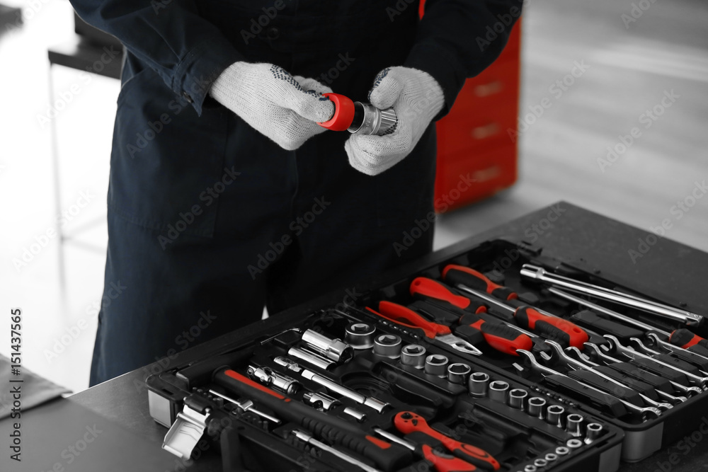 Auto mechanic with tools in car repair shop, closeup