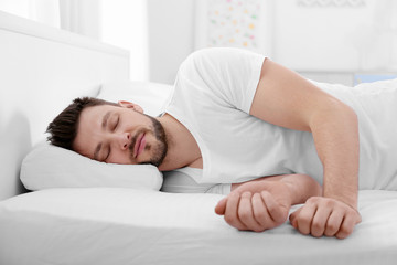 Wall Mural - Young man lying on bed with orthopedic pillow at home