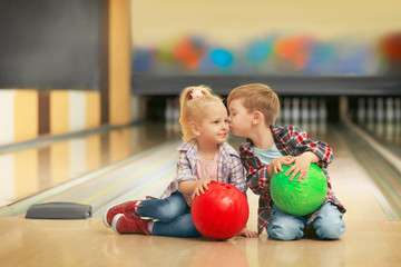 Canvas Print - Cute little children with balls sitting on floor in bowling club