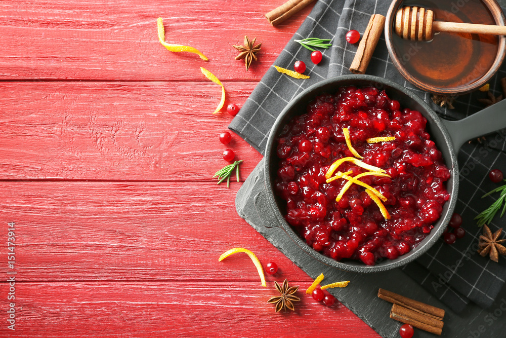 Delicious cranberry sauce in pan on wooden background, top view