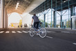 © serejkakovalev - young man riding on bicycle in city street. Man on blue bicycle with white wheels, big mirror windows background