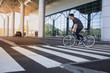 © serejkakovalev - Side view portrait of a young man riding on bicycle in city street. Man on blue bicycle with white wheels, big mirror windows background