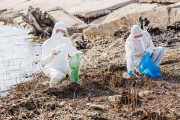 Ecologysts working together on cleaning up garbage on the shore of the lake.