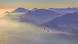 Paraglider flying over the mountains and lake during sunset. Pastel colors background. Garda lake, Italian Alps