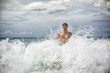 © theartofphoto - Handsome young man standing on a beach in Phuket Island, Thailand, getting hit by big wave's splash