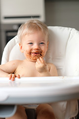 Toddler baby boy child eating fruit with dirty messy face