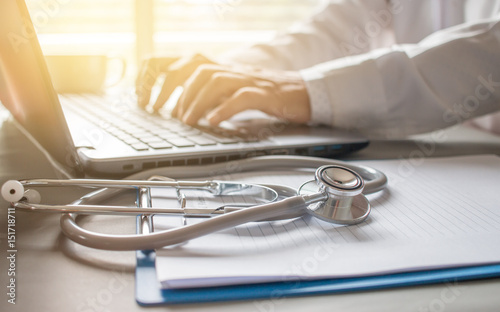 Fotografía Stethoscope on prescription clipboard and Doctor working an Laptop on desk in ho