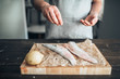 Chef hands salting raw fish over cutting board
