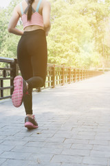 Female sport fitness runner jogging outdoors on bridge in spring or summer. Healthy young asian woman running in park.