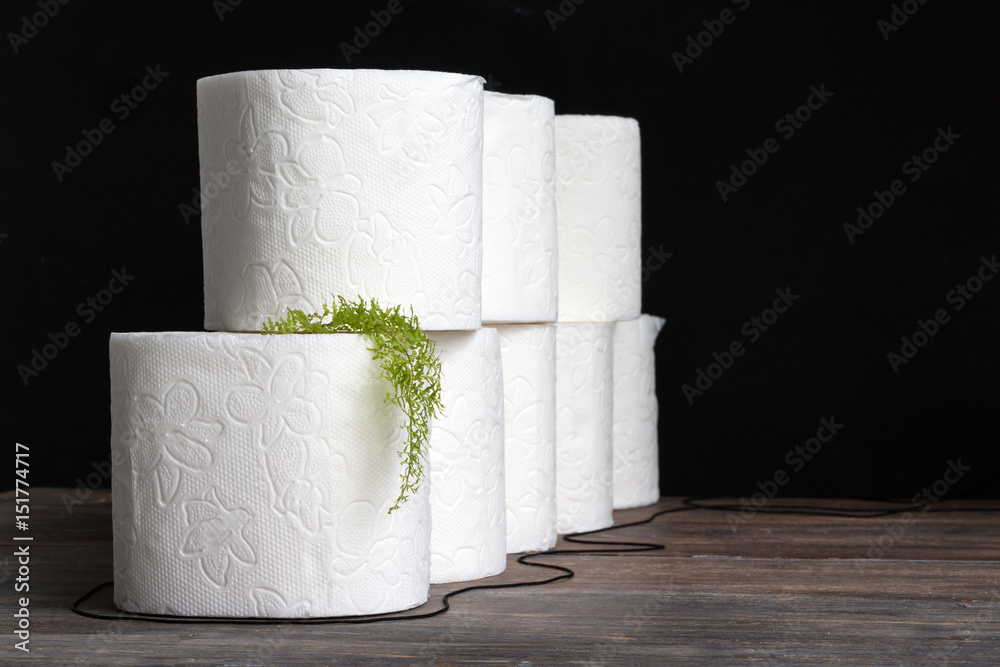 Toilet paper stack on wooden table against black background. Copy space ...