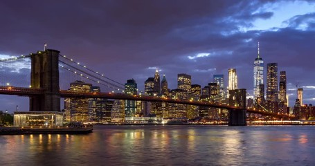 Fototapete - Time-lapse of Lower Manhattan Financial District skyscrapers, Brooklyn Bridge, and East River with passing clouds at twilight. Manhattan, New York City