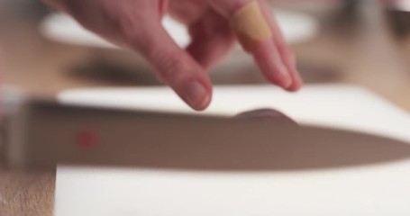 Wall Mural - Slide shot of young female hand cutting raw beef with a knife on plastic board, 4k 60fps prores footage