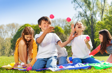 Happy kids juggling with little balls in the park