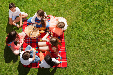 Friends sitting near picnic basket on green meadow