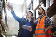 © pressmaster - Businessman with touchpad pointing at upper shelf with goods while talking to worker