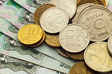 A handful of Russian coins of different denominations against the background of one thousand bills