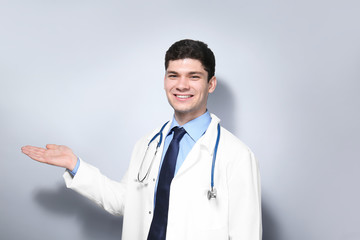 Wall Mural - Handsome young doctor on light background