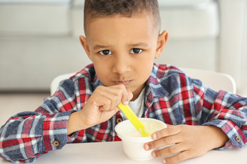 Wall Mural - Cute African American boy eating yogurt at home
