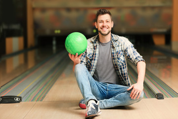 Canvas Print - Handsome young man with ball in bowling club