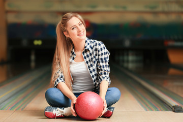 Canvas Print - Beautiful young woman with ball in bowling club