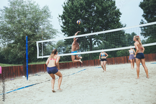 Zdjęcie XXL Grupa młodzi ludzie bawić się plażową siatkówkę na pięknym słonecznym dniu.