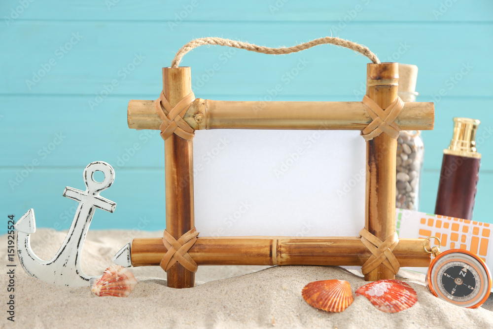 Travel concept. Bamboo frame with space for text and travel accessories on sand against color background