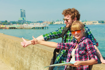 couple backpacker with map by seaside hitchhiking