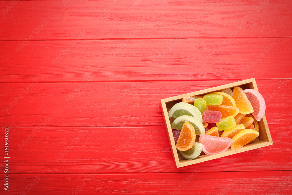 Box with tasty jelly candies on wooden background