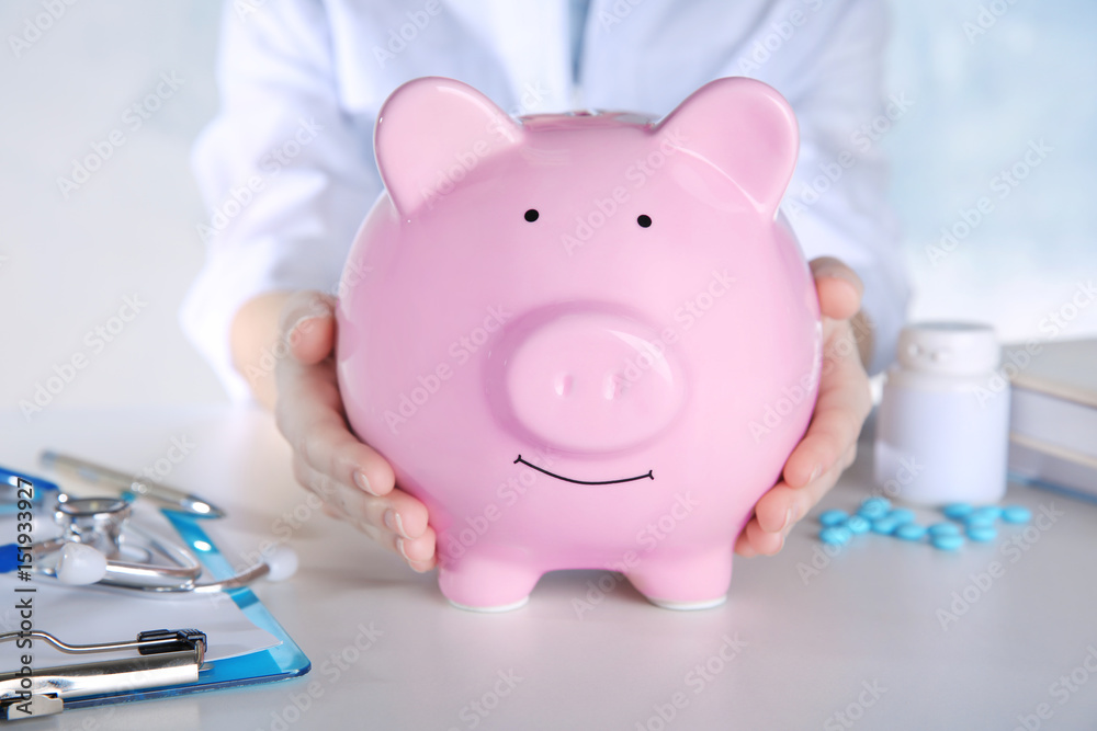 Doctor's hands with piggy bank, closeup
