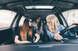 © F8  \ Suport Ukraine - Road trip with beauties. View of two beautiful young cheerful women looking back at third girl with smile while sitting in car